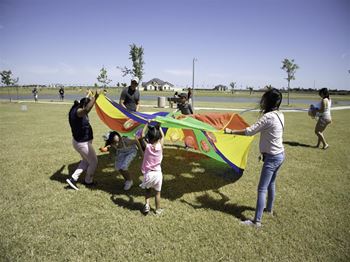 A group of people are flying a colorful kite in a grassy field.