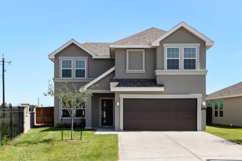 A two-story house with a garage door and a tree in front.