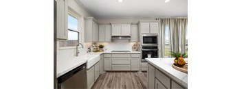 A kitchen with a white countertop and a window with curtains.