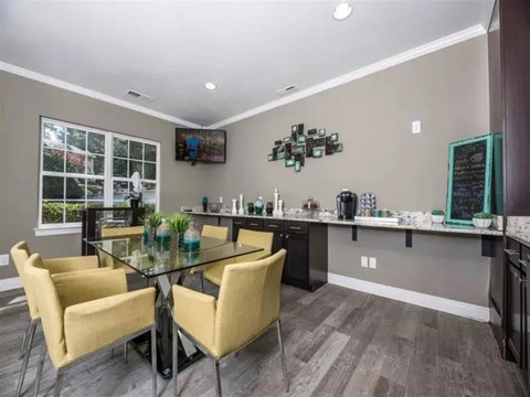 A modern kitchen with a glass table and yellow chairs.