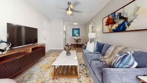 A living room with a grey couch, a wooden coffee table, and a painting on the wall.
