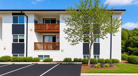A white apartment building with a black parking lot in front.