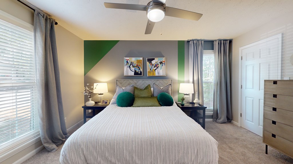 A bedroom with a large bed and a ceiling fan.