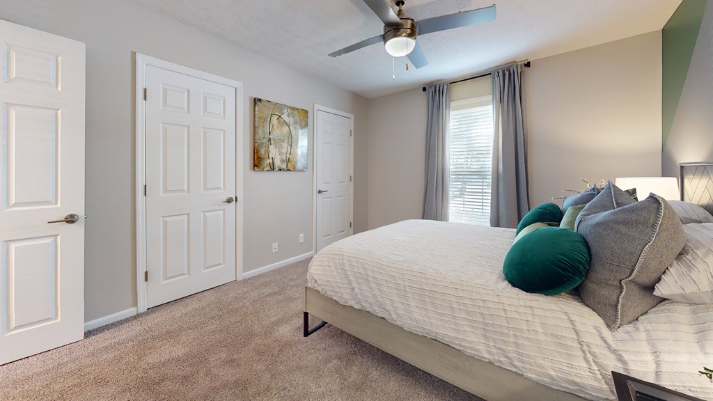 A bedroom with a bed, pillows, and a ceiling fan.