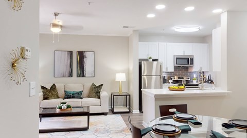 A modern kitchen and living room with a dining table set for two.