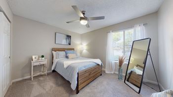 A bedroom with a bed, nightstand, and a ceiling fan.