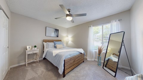A bedroom with a bed, nightstand, and a ceiling fan.