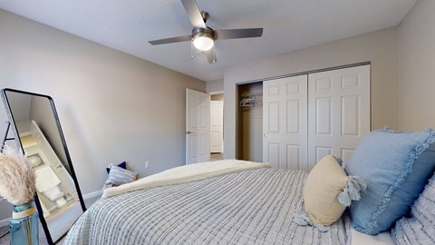 A bedroom with a bed, pillows, and a ceiling fan.