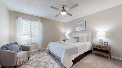 A bedroom with a bed, chair, and a ceiling fan.