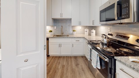 A modern kitchen with white cabinets and a black stove top.