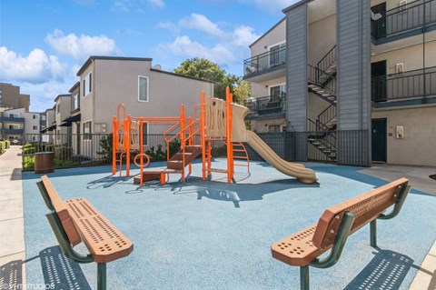 A playground with a slide and swings in front of a building at Oak Center Apartments, Oakland, California