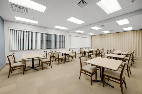 A room with tables and chairs and a window with bars.