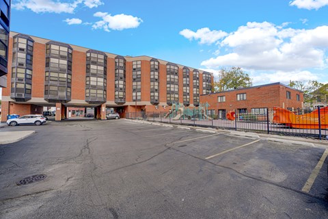 A parking lot in front of a multi-story brick building.
