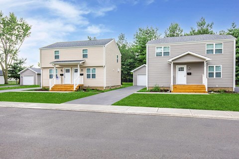 Two houses are side by side with a road in between.