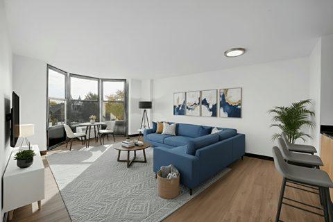 A modern living room with a blue sofa and a grey rug.