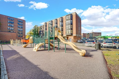 A playground with a yellow slide in front of a building at Fullerton Court Apartments, Chicago, IL 60614