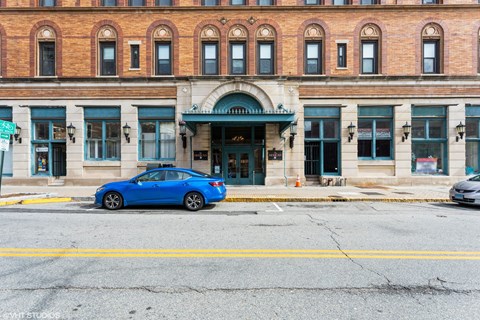A blue car is parked in front of a building with a green awning. A blue car is parked in front of a building with a green awning at Mohican Apartments, New London, Connecticut