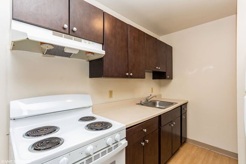 A white stove in a kitchen with brown cabinets. A white stove in a kitchen with brown cabinets at Mohican Apartments, New London, Connecticut