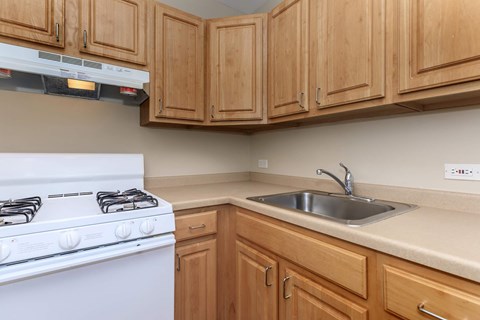 A white gas stove is in a kitchen with wooden cabinets.