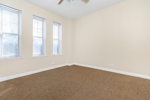 A room with a carpeted floor and a ceiling fan.