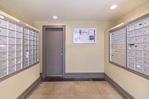 A hallway with a wall of mailboxes on the left and right, and a door in the middle.