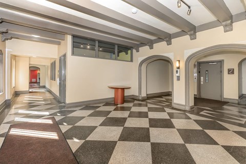 A hallway with a checkered floor and a brown carpet.