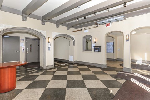 A hallway with a black and white checkered floor and a red reception desk.