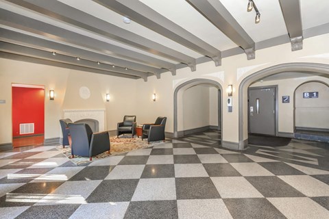 A hallway with a checkered floor and a red door.