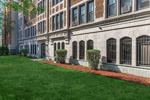 A building with a long row of windows and a green lawn in front.