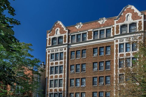 A tall red brick building with a clock on the top floor.