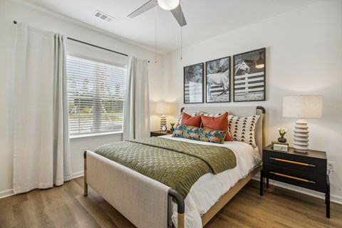 A bedroom with a bed, nightstand, and pictures on the wall.