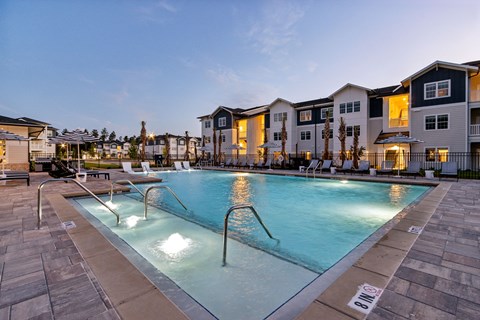 A swimming pool surrounded by a stone walkway and a building in the background.
