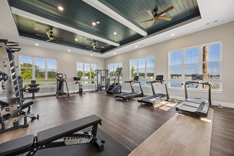 A spacious gym with treadmills, elliptical machines, and a weight bench.