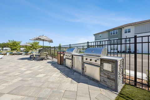 A patio with a stone oven and a striped umbrella.