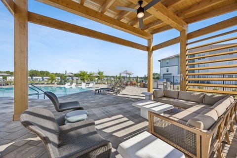 A wooden patio with a table and chairs overlooking a pool.