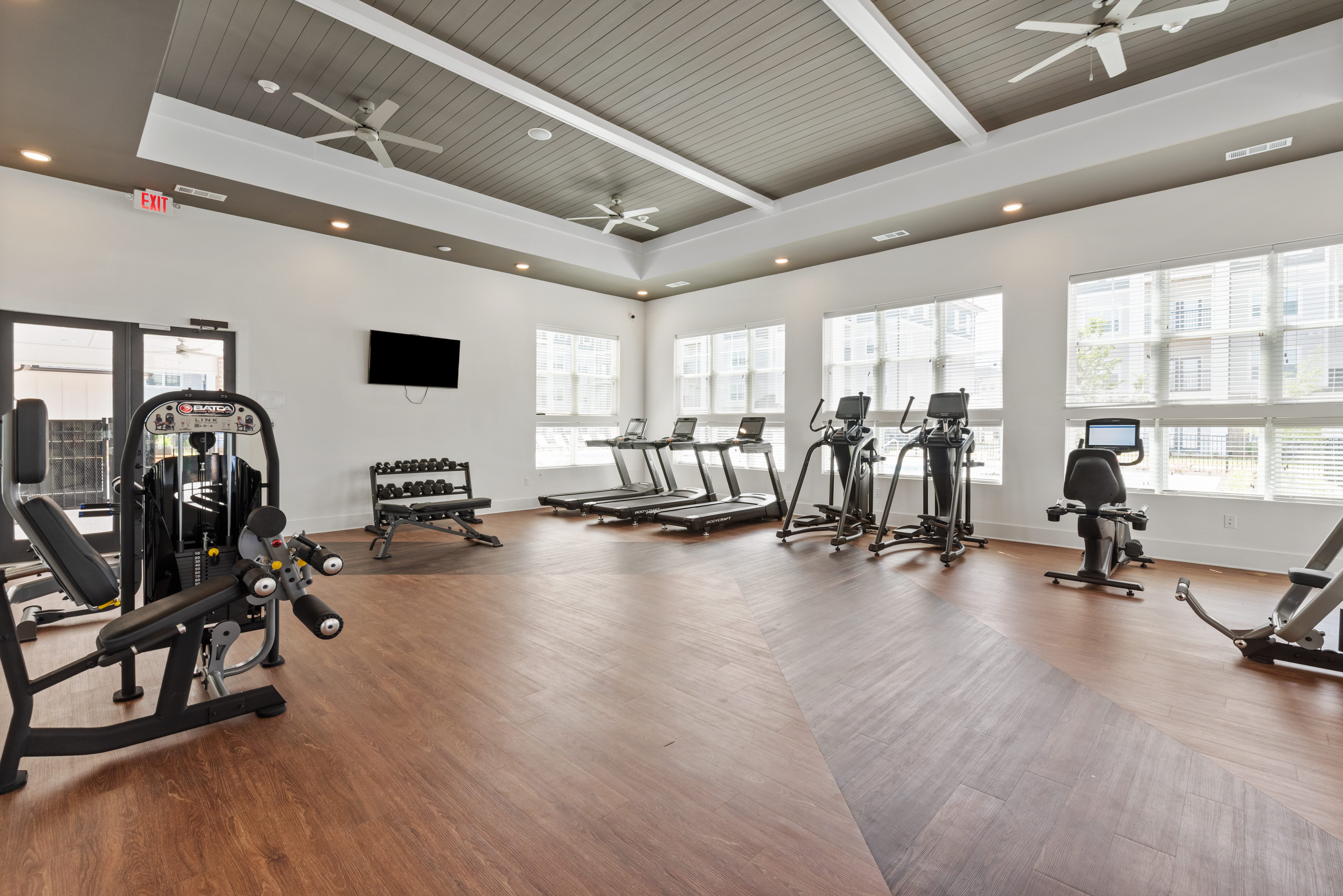A gym with a variety of equipment including treadmills, weights, and a television.