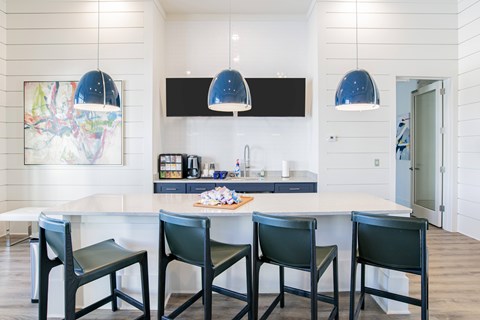 A modern kitchen with a white table and black chairs.