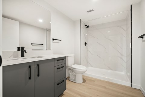 A white bathroom with a marble shower wall.
