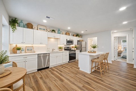 A kitchen with white cabinets and wooden floors.