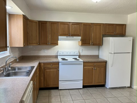 A kitchen with white appliances and wooden cabinets.