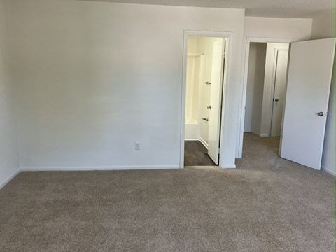 A room with a carpeted floor and two doors.