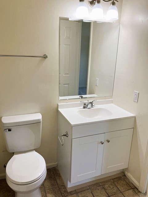 A white toilet sits next to a white sink in a bathroom.