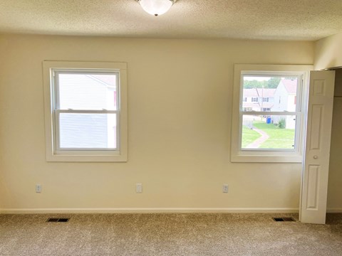 A room with a window and a door leading to a view of a street.