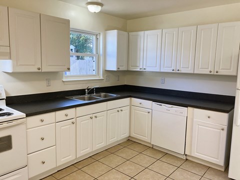 A kitchen with white cabinets and black countertops.