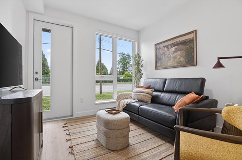 A living room with a black leather couch and a flat screen TV.