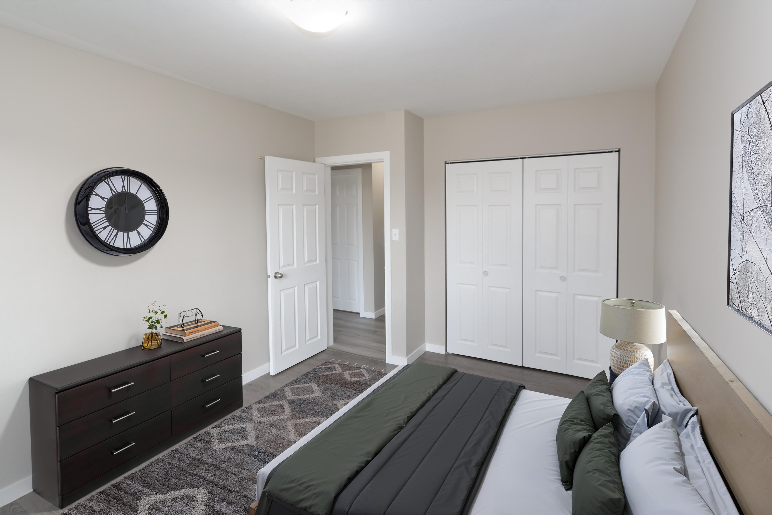 A bedroom with a bed, dresser, and a clock on the wall.