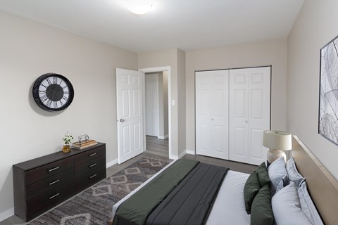 A bedroom with a bed, dresser, and a clock on the wall.