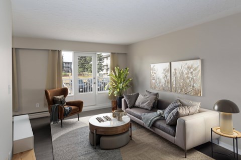A living room with a grey couch, a brown armchair, a coffee table, and a floor lamp.