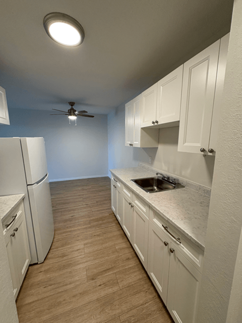 A kitchen with white cabinets and a ceiling fan.