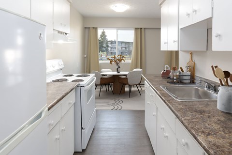 A kitchen with white cabinets and a marble countertop.